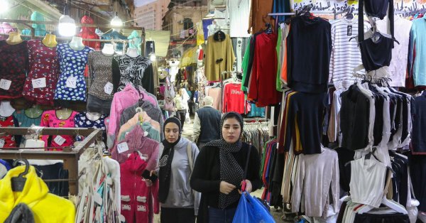 Жени се разхождат сред магазините на нощен пазар в Александрия