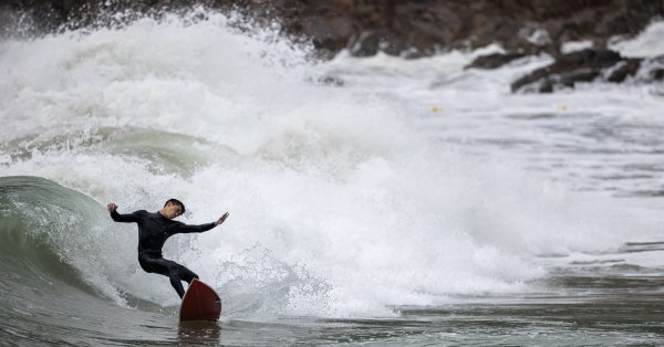 Мъж сърфира на вълните донесени от тайфуна Несат в Хонконг