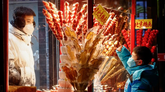 Дете купува традиционен китайски сладкиш в търговския квартал на Пекин