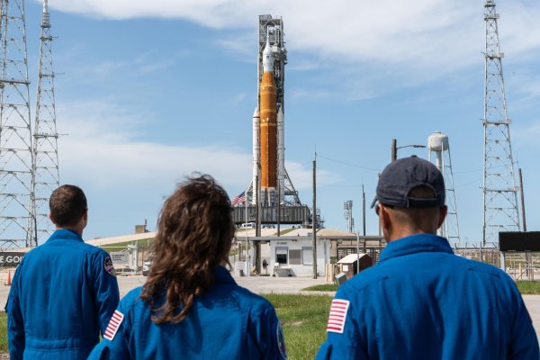 От ляво на дясно астронавтите на НАСА Рийд Уайзман, Кристина Кох и Джо Акаба разглеждат системата за изстрелване на космически кораби Space Launch System и космическия кораб "Орион". Снимка: NASA/Josh Valcarcel.
