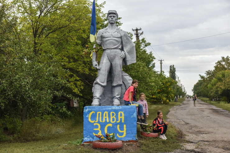 Деца седят на паметник, изрисуван с думите "Слава на ВСУ" (Въоръжените сили на Украйна) в Харковска област, Североизточна Украйна, 17 септември 2022 г.  EPA/OLEG PETRASYUK